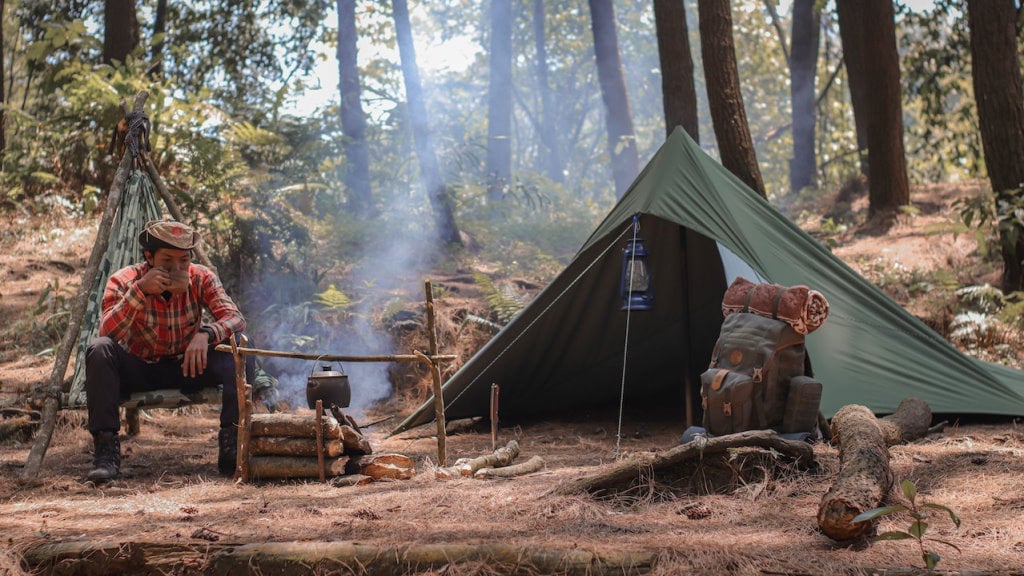 A man starting his day with a cup of tea at camp