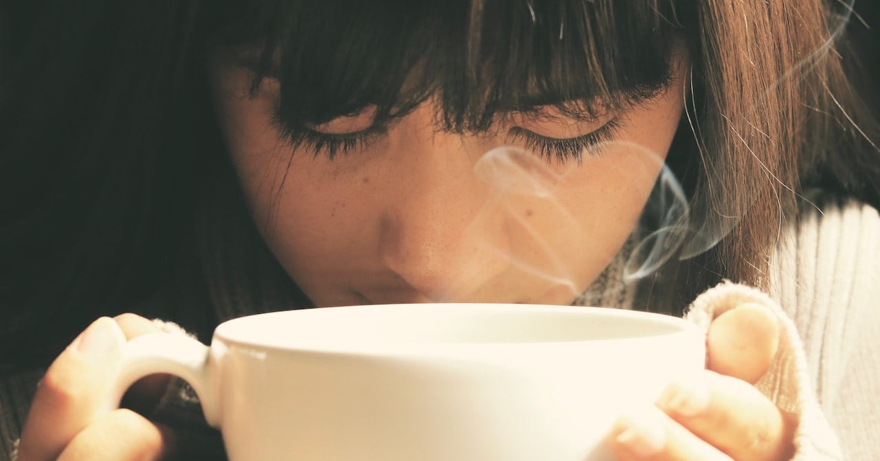 A woman drinking hot tea from a mug