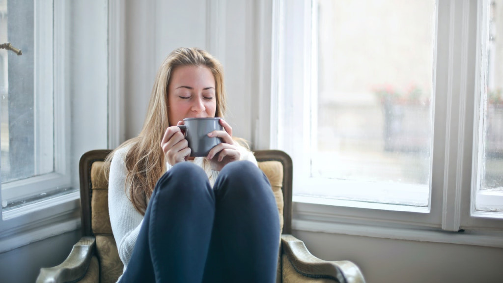 A woman smiling while drinking tea