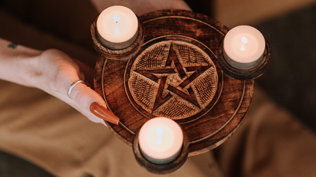 Witch showing pentagram sign with candles