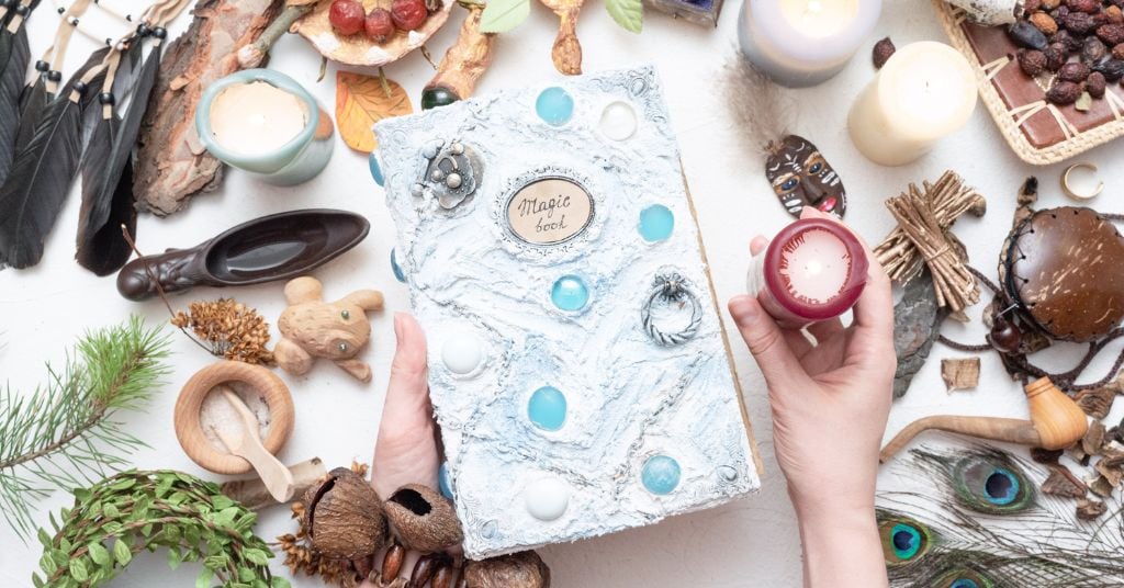 Hands holding a Magic book in front of table with magic items