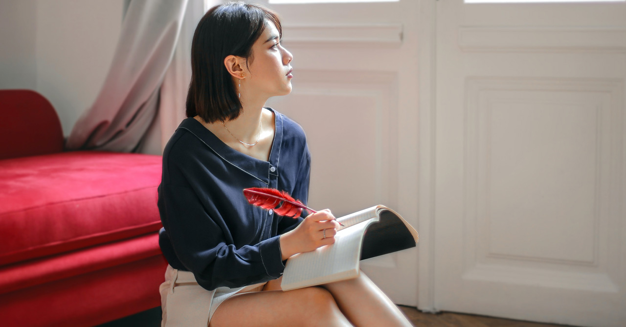 Thoughtful woman writing in notebook at home