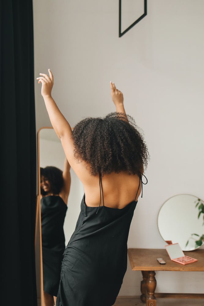 A woman dancing alone in front of mirror