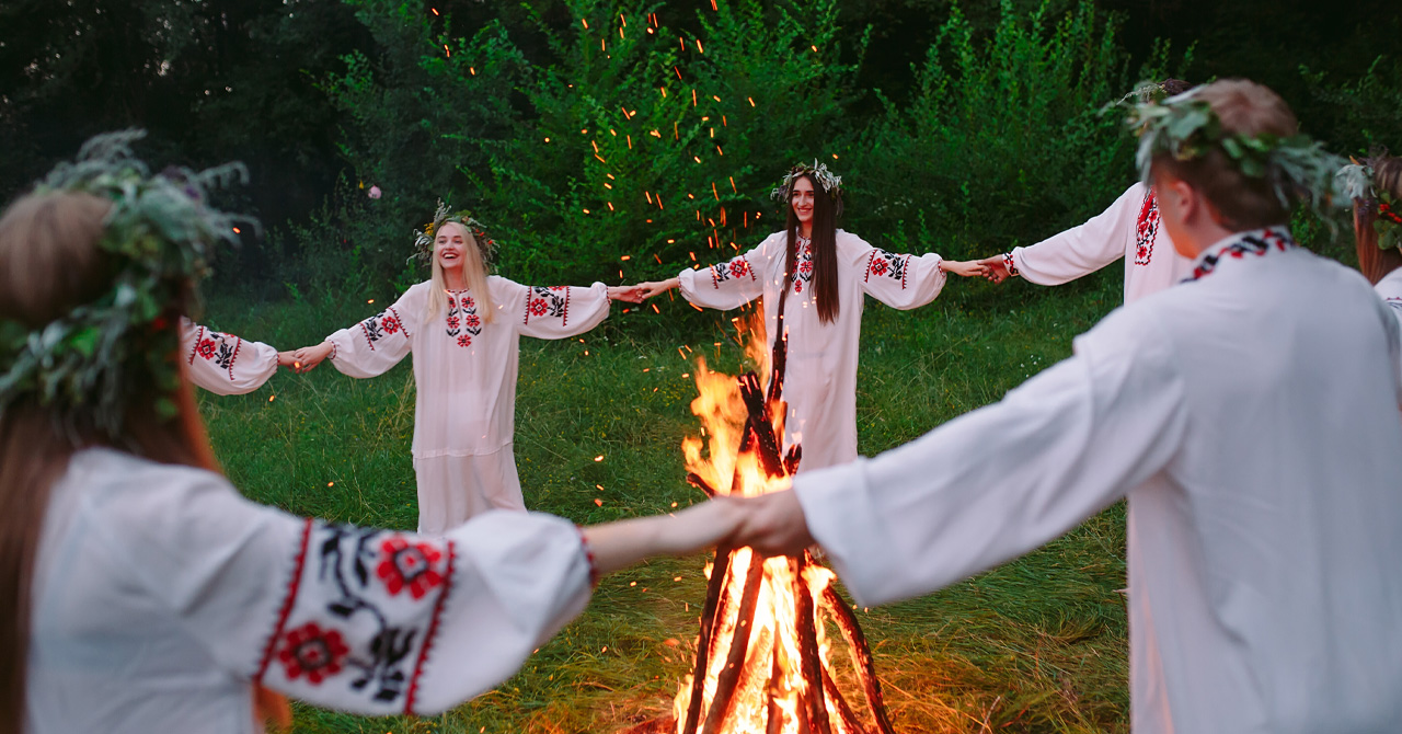 Young people in a circle dance around a bonfire in the forest